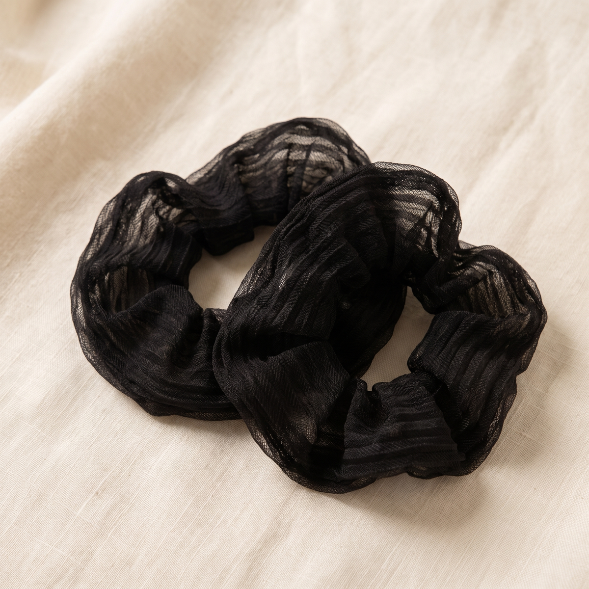 Moonspot silk scrunchies laid on warm cream linen