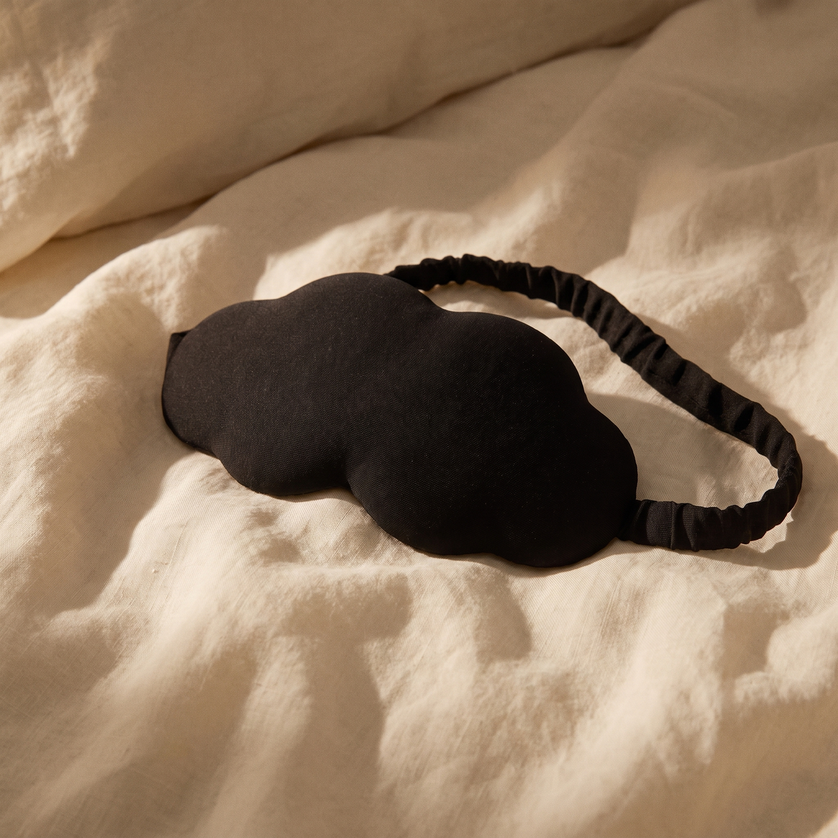 Moonspot blackout sleep mask resting on cream linen bedding