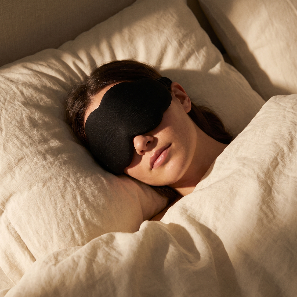 Blackout sleep mask worn while sleeping on cream linen